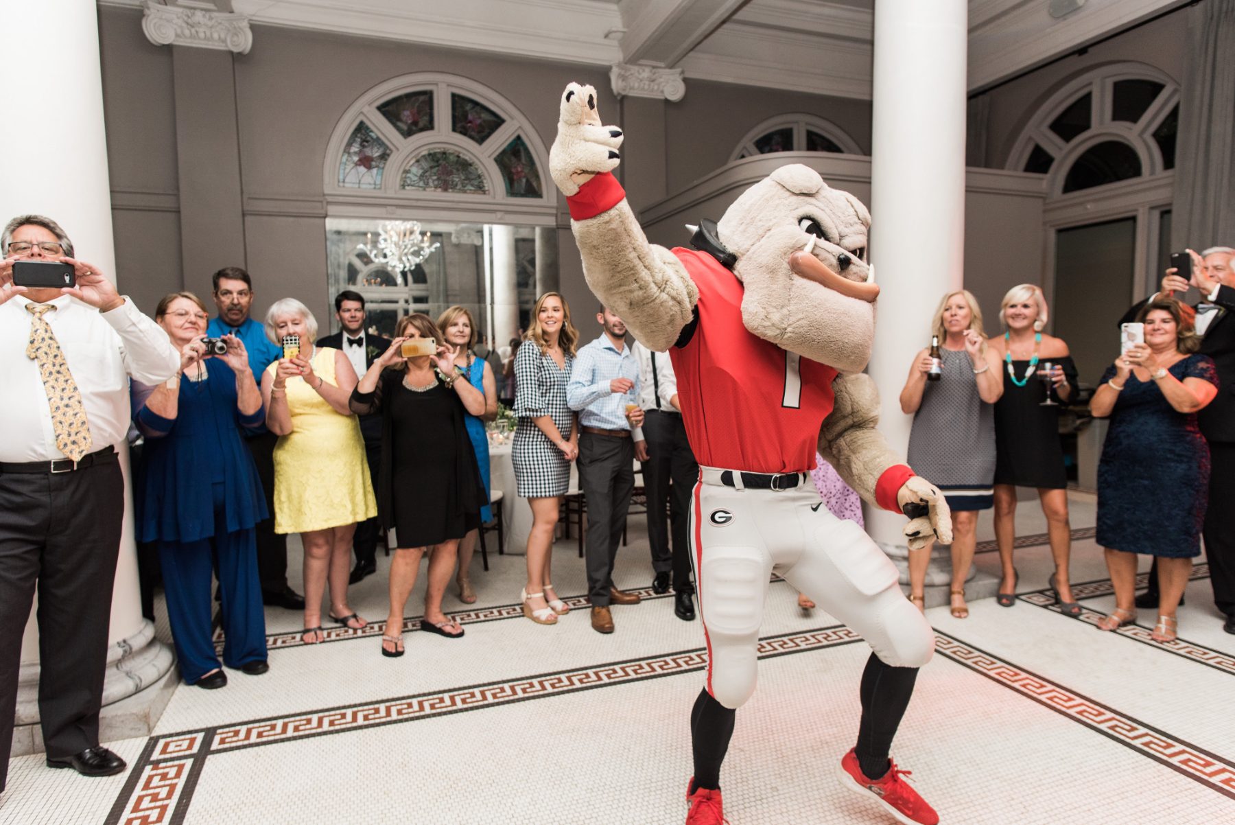 Hairy Dawg dancing while guests film on their phones at a wedding reception in a historic downtown Athens, Georgia venue