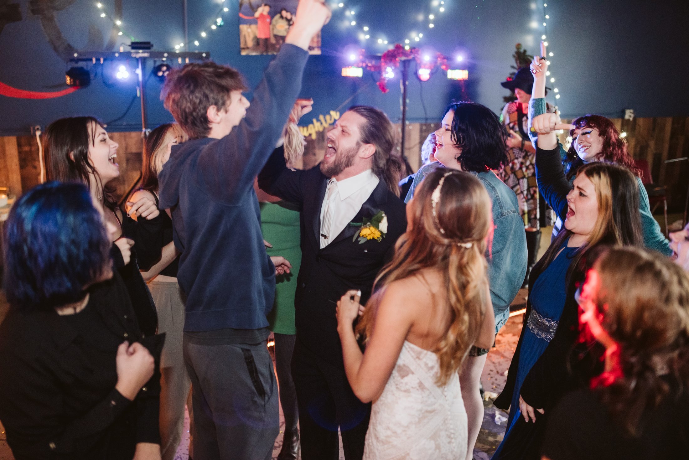The couple and their guests singing with their hands up on a packed dance floor under string lights at a north Georgia reception