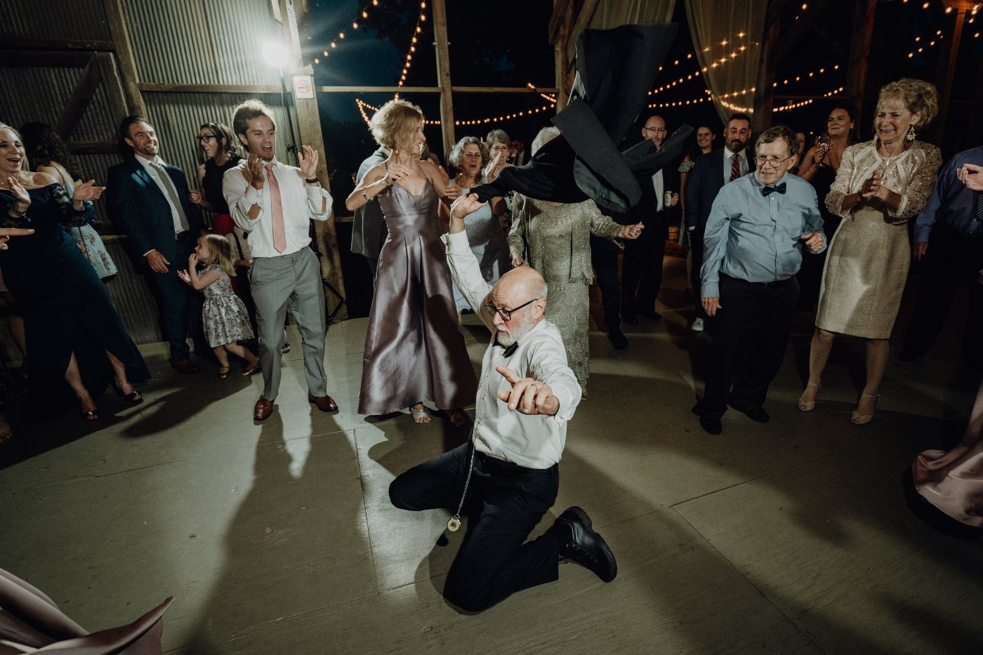 A father of the bride dancing on one knee inside a ring of guests at a north Georgia reception