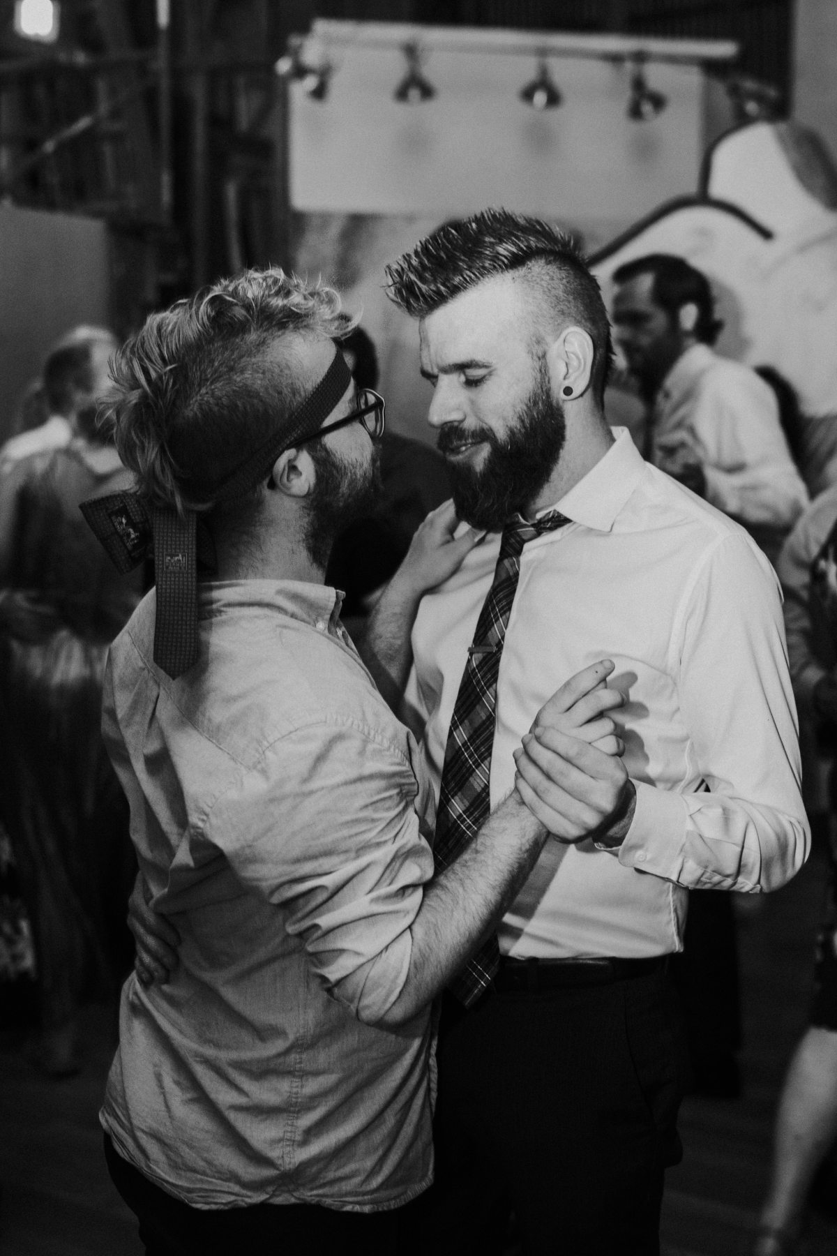 Two grooms slow dancing together late in a wedding reception