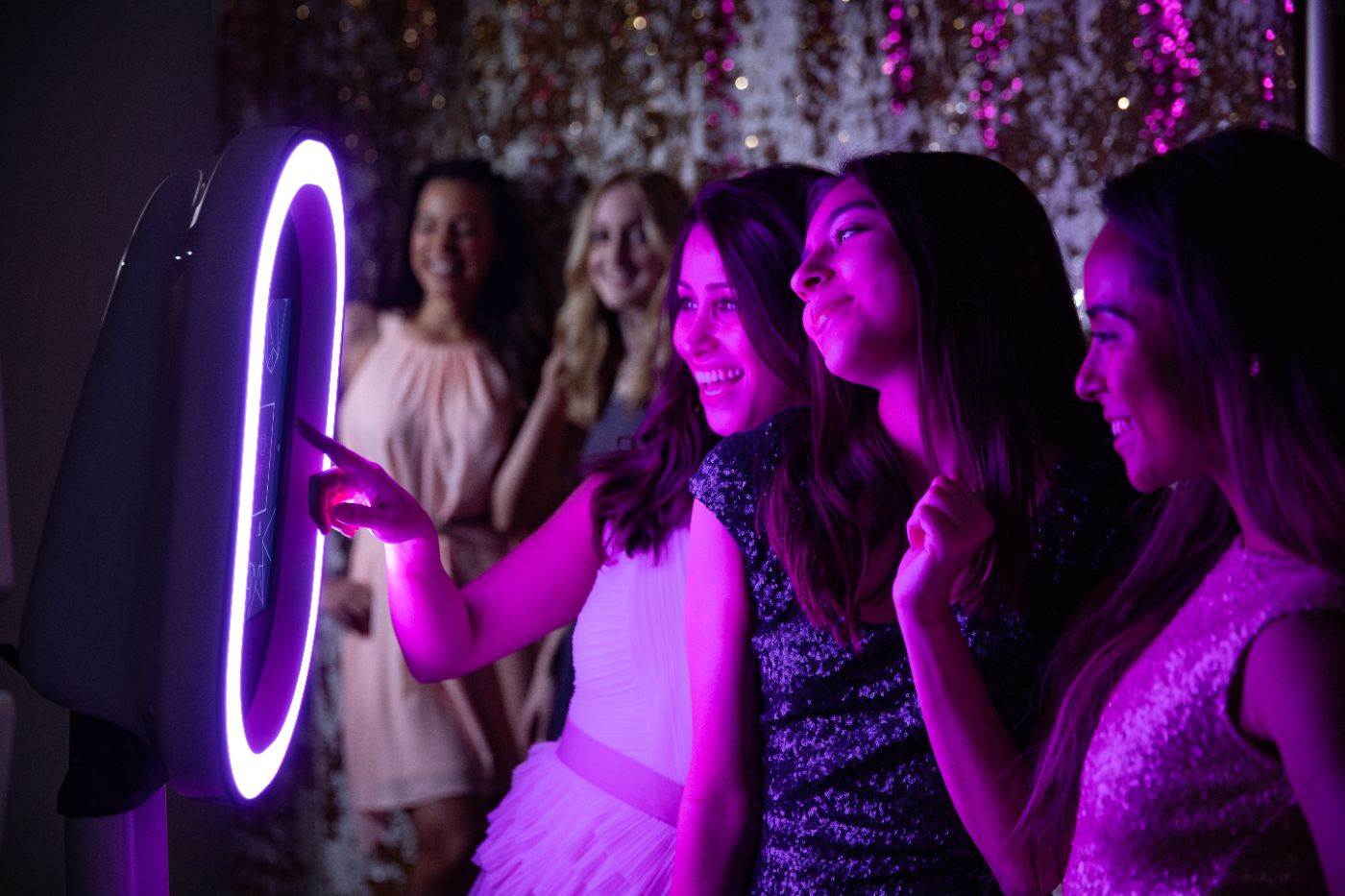 Guests tapping the Nightbird Social Booth screen while their friends wait to jump in