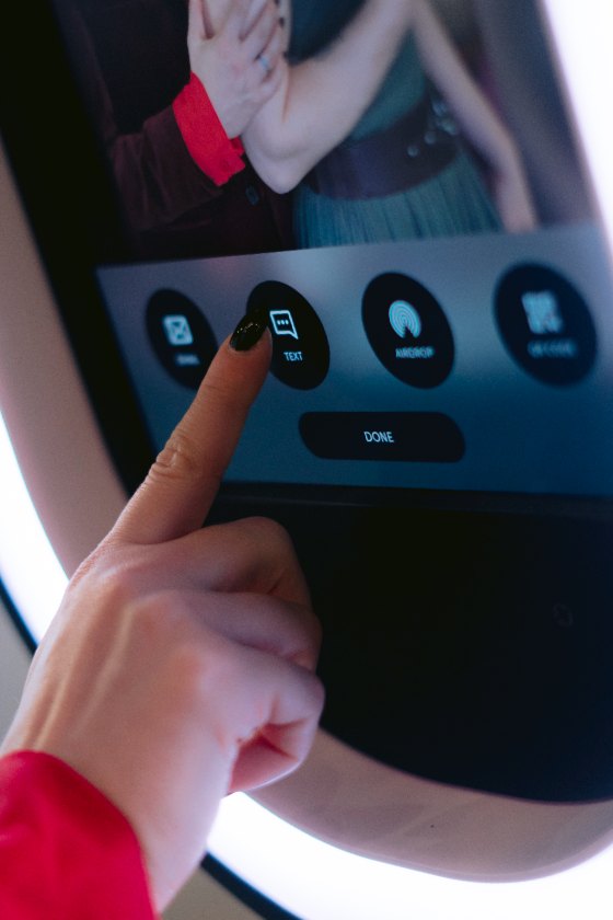 A guest tapping the text-message option on the booth screen to send her photo to her phone