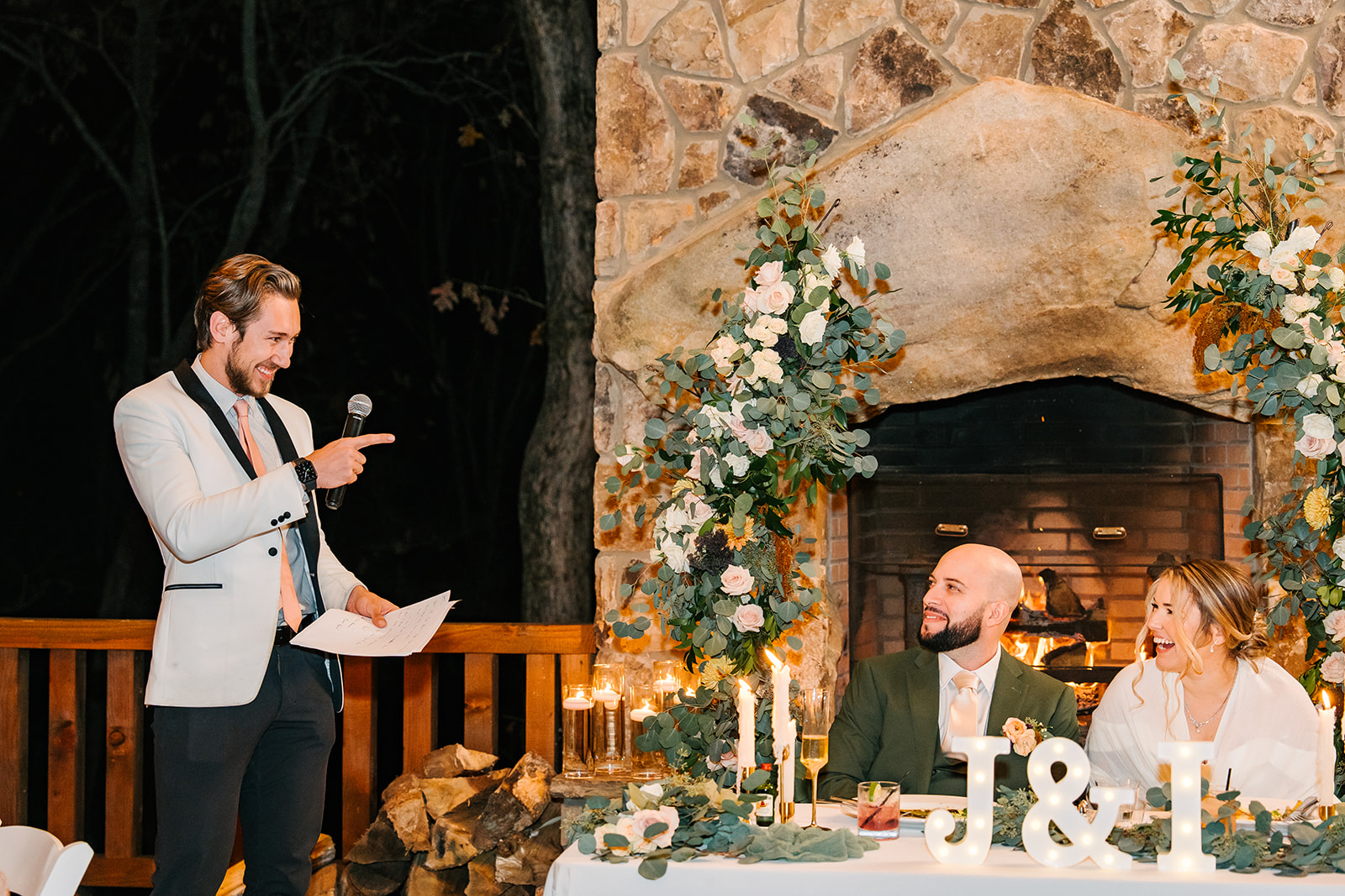 A Nightbird DJ on the mic in a white jacket while the couple laughs at their table